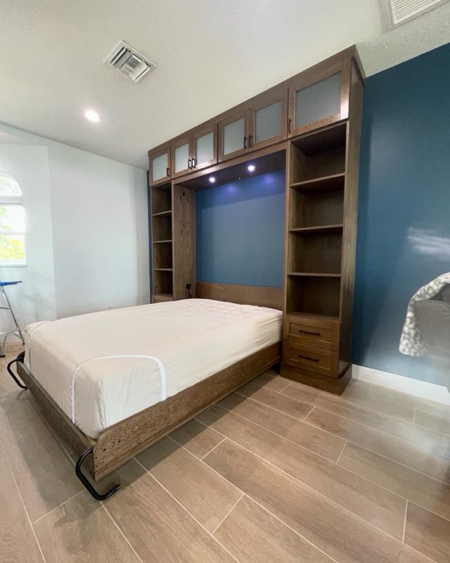 Wood Murphy wall bed with matching side towers of shelving against a deep blue accent wall